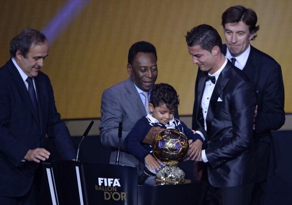 Real Madrid's Portuguese forward Cristiano Ronaldo (front-R) holds the 2013 FIFA Ballon d'Or award for player of the year with his son Cristiano Ronaldo Junior